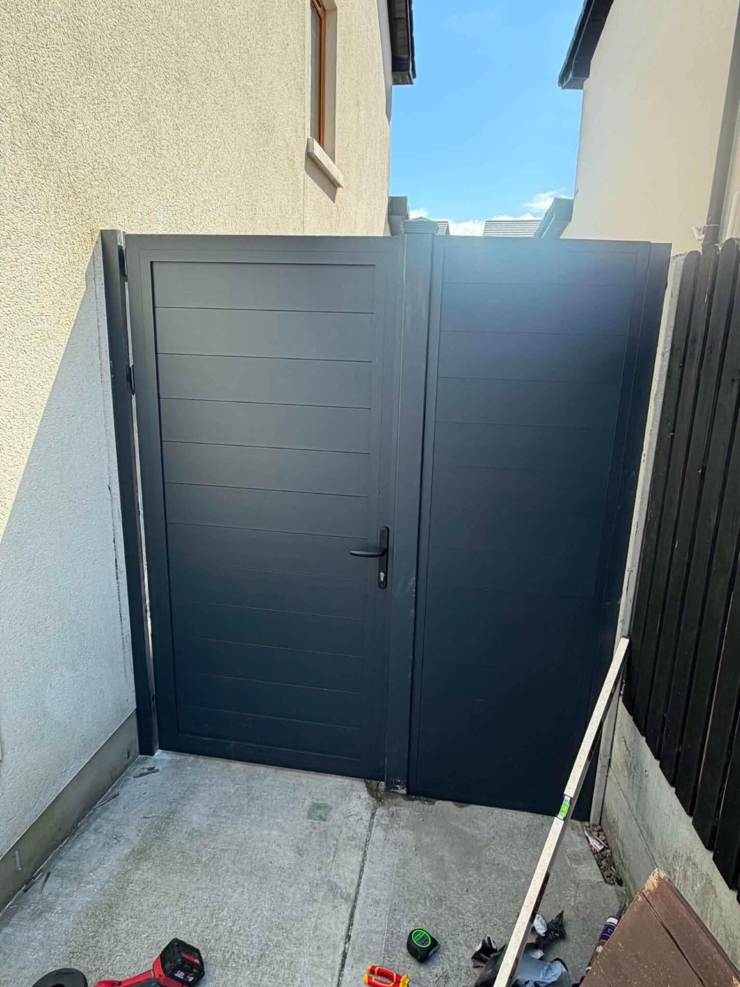 Anthracite aluminium side gate with a matching fixed panel between two houses