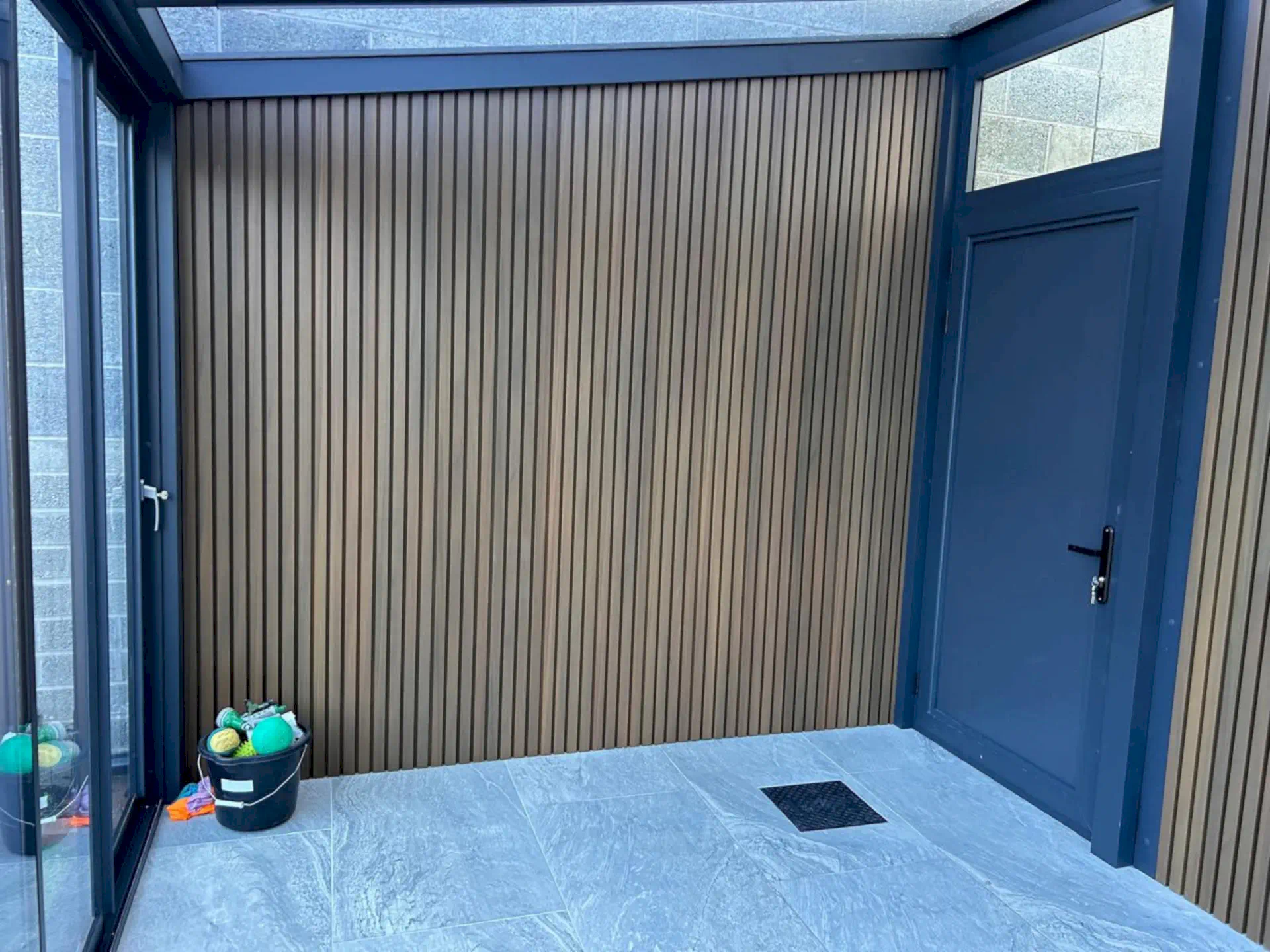Composite cladding wall with an entrance door from the side path into the pergola