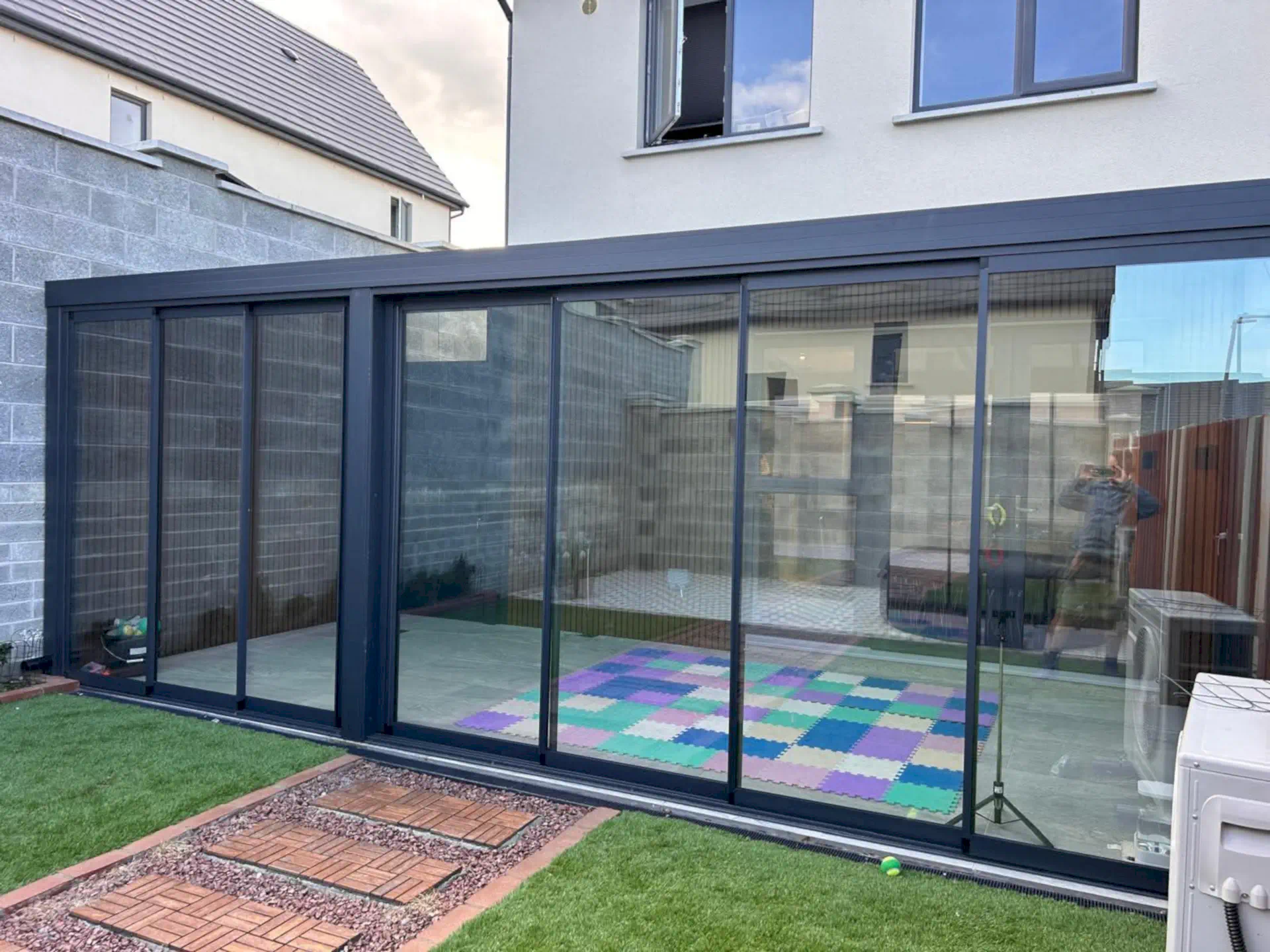 Aluminium veranda with sliding glass walls across the back of a house